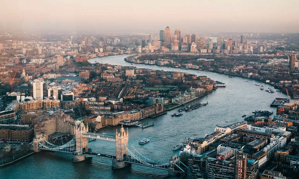 Panoramic aerial view of London showing Tower Bridge over the River Thames and the surrounding cityscape.